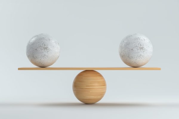 wooden scale balancing two big balls in front white background